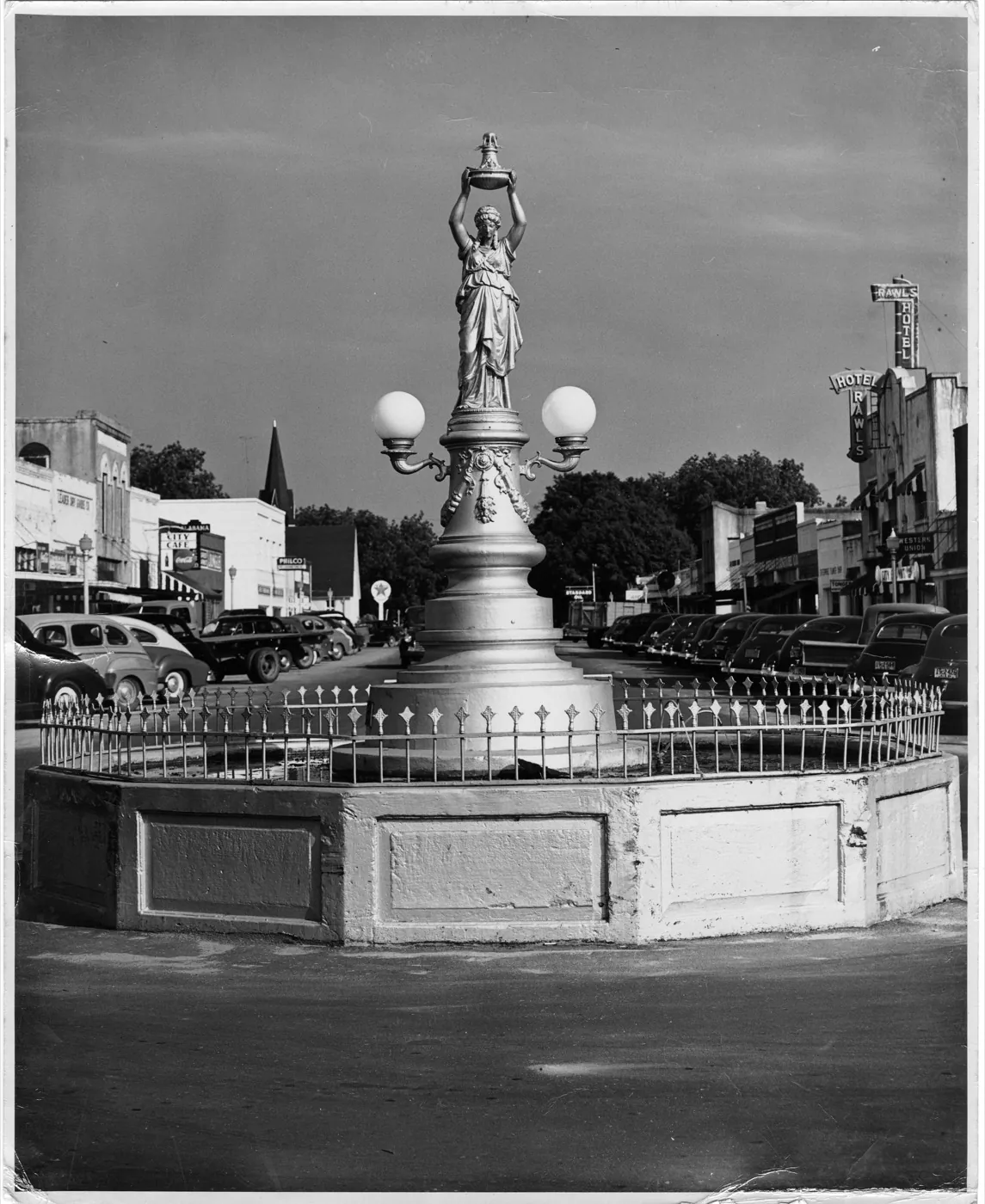 A historic black-and-white photograph of the Boll Weevil Monument fountain on Main Street